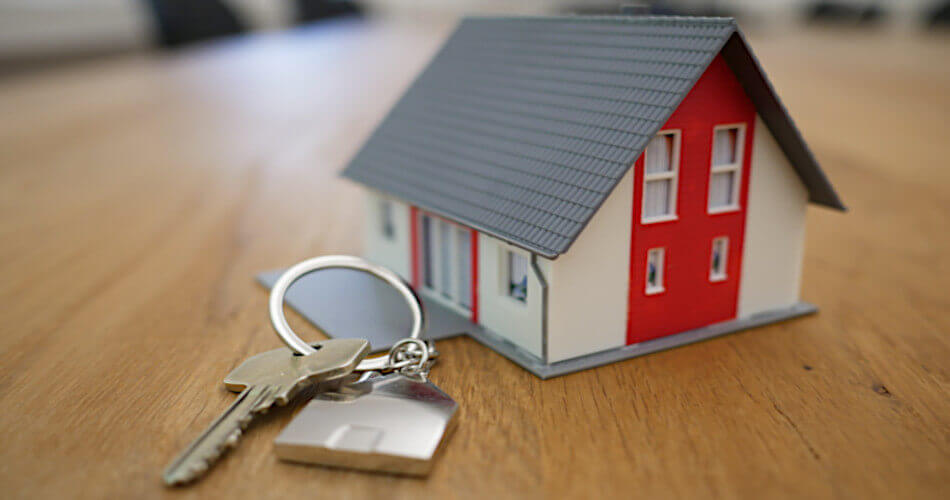 Small model of a home and some keys, symbolizing home ownership