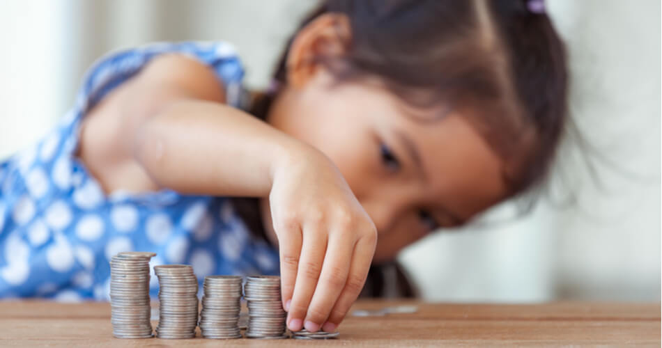 Little girl stacking coins on a table