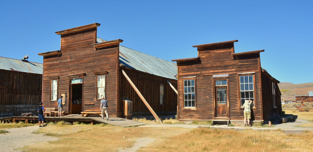 Two old store-fronts with three people looking in the windows