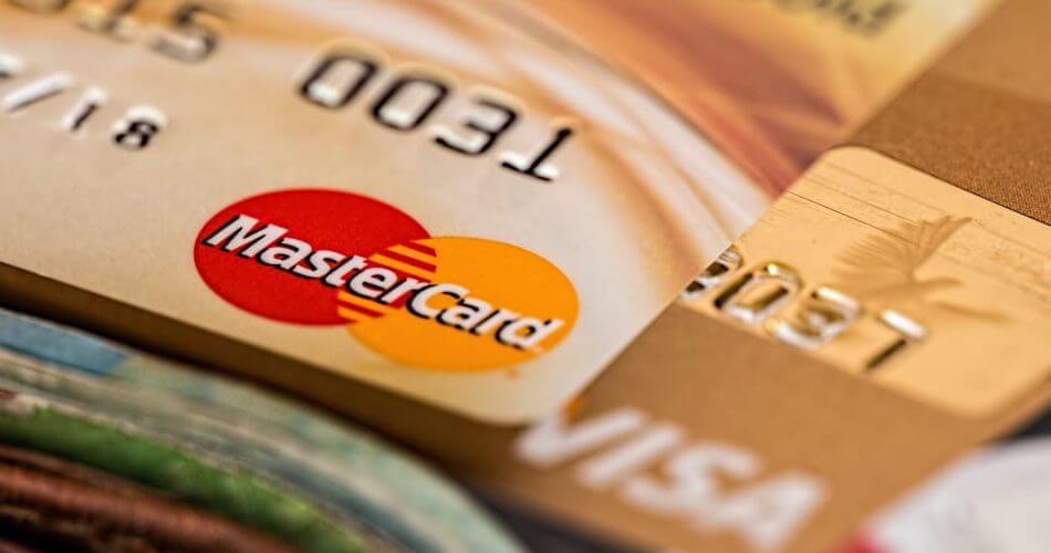 mastercard on top of visa card on top of wallet with some cash