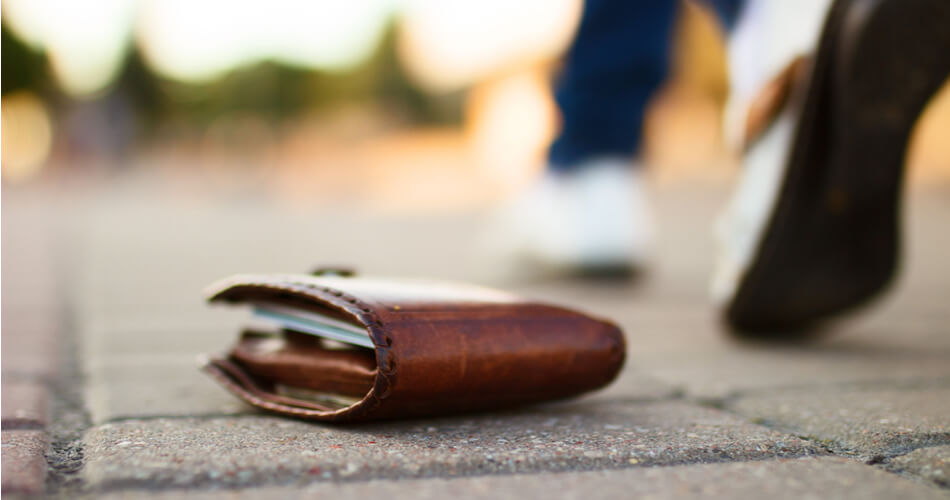 Wallet sitting on the ground with a person walking away in the background